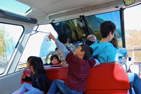 A family with small children riding the Seattle Center Monorail to Seattle Center. One child is pointing up through the window at the Space Needle.