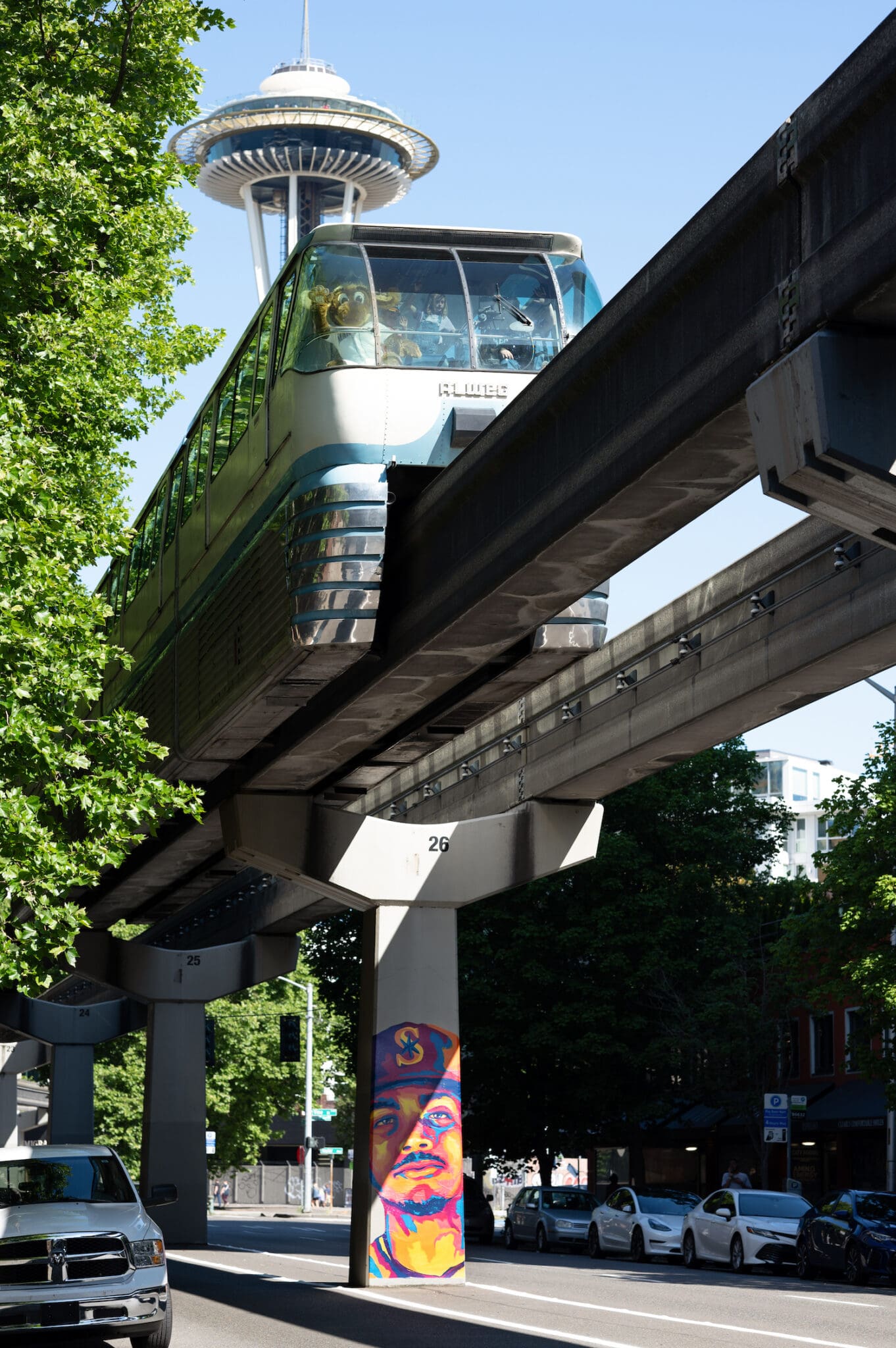 Julio Rodriguez mural on monorail column with Monorail and the Space Needle. The Mariner moose is inside the monorail waving to the camera